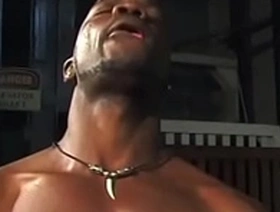 Bald black male in white muscle shirt sucks a dick